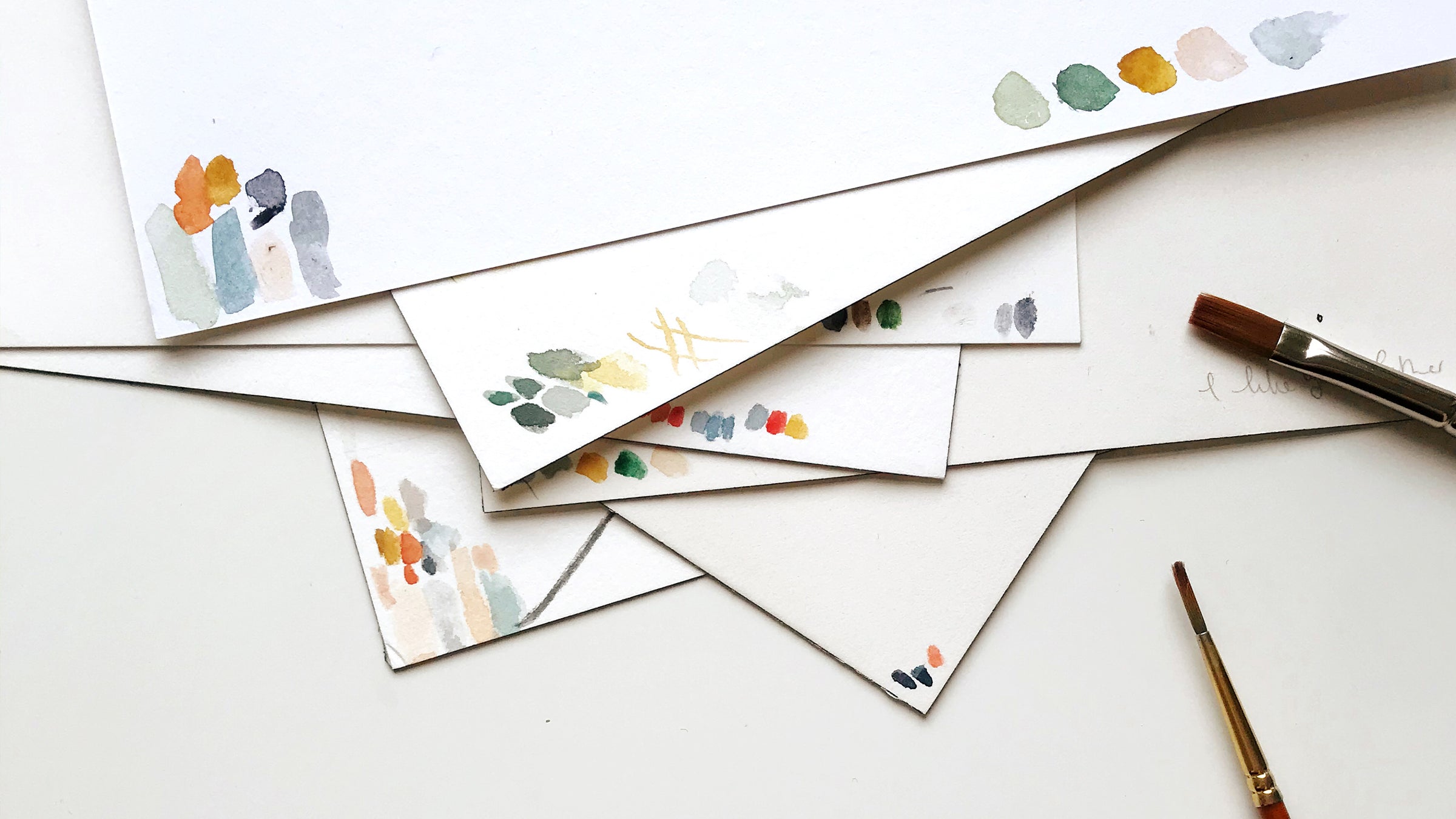 A pile of paper with watercolour paint colour testers