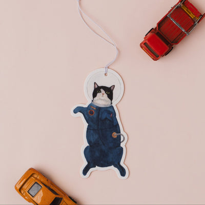 Cat-shaped air freshener with toy cars on a pink background