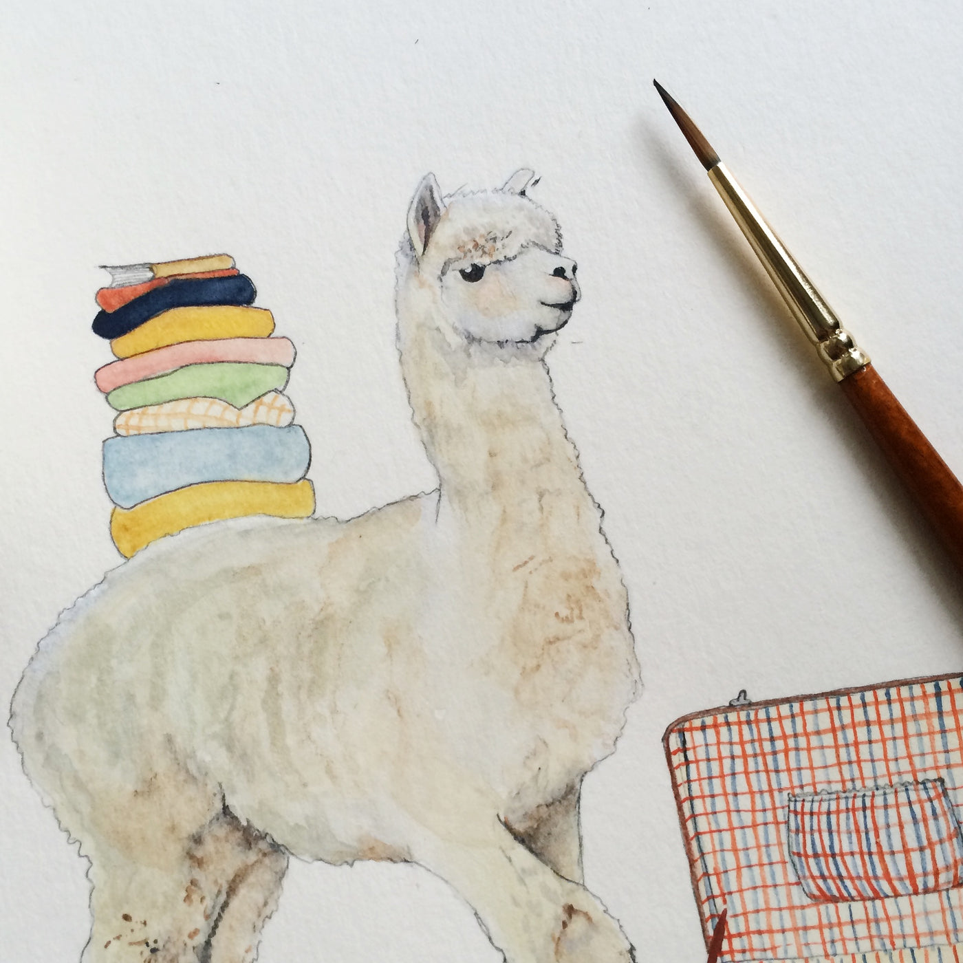 Close up of alpaca illustration with suitcase and stack of clothes.